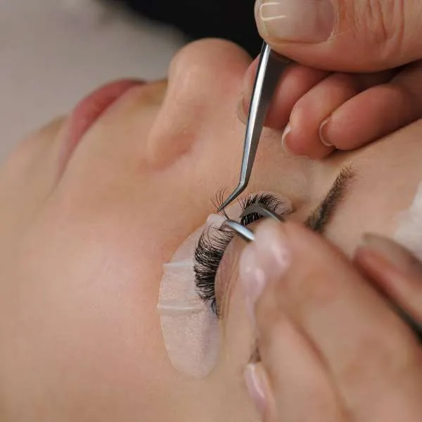 Best fake lashes being carefully applied with tweezers for a natural-looking everyday lash style
